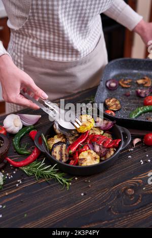 Verdure alla griglia in ceramica nera piastra sul tavolo in cucina domestica Foto Stock