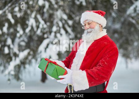 Vita in su ritratto di Babbo Natale tradizionale tenere presente all'aperto nella foresta invernale Foto Stock