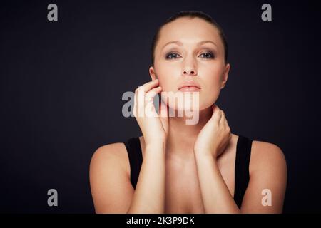 Controllo della pelle. Studio ritratto di una bella giovane donna che tocca la sua pelle. Foto Stock