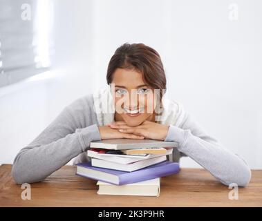 Non vediamo l'ora di rimanere bloccato. Un giovane studente universitario che si appoggia sui suoi libri e sorride. Foto Stock