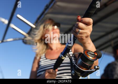 Primo piano di donna che pesca con canna da pesca in mare Foto Stock