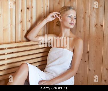 Non una cura nel mondo. Uno scatto corto di una bella giovane donna che si rilassa nella sauna. Foto Stock