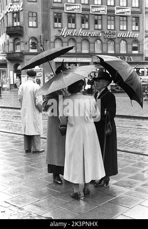 Ombrelloni nel 1950s. Un gruppo di donne anziane si trova sotto gli ombrelli. E' una giornata piovosa a Stoccolma Svezia 1953. rif 2A-1 Foto Stock