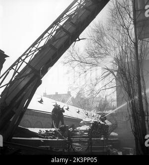 Fuoco negli anni '1940s. I vigili del fuoco e i vigili del fuoco si vedono con le manichette che spruzzano acqua su un edificio in fiamme. E' nel centro di Stoccolma durante l'inverno. Svezia 1945 Kristoffersson Ref M128-1 Foto Stock