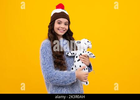 Ragazza teen in abiti casual tenere giocattolo morbido per il compleanno su sfondo giallo. Bambino che passa il tempo con i suoi giocattoli. Felice adolescente, positivo e sorridente emo Foto Stock