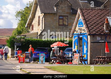 Turisti al di fuori del negozio di articoli da regalo Scripps Funeral Services, utilizzato come location per le riprese di Aidensfield Garage nella serie televisiva 'Heartbeat' Foto Stock