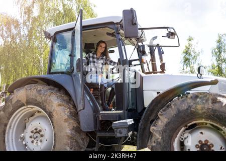 Ritratto di donna sorridente alla guida di un trattore Foto Stock