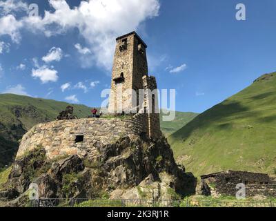 Un'antica fortezza in pietra nel villaggio di Sno sullo sfondo di montagne e prati alpini Foto Stock