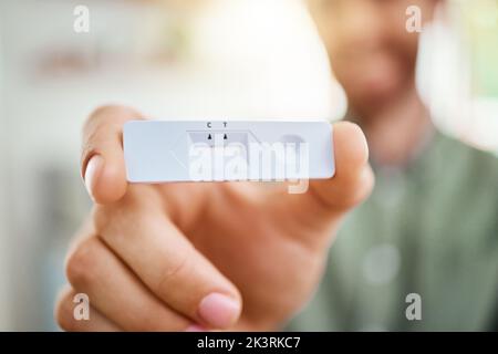 Covid, test antigenico rapido e mani con un risultato negativo su un kit di test in mano di un uomo durante la pandemia. Salute, medico e assicurazione Foto Stock