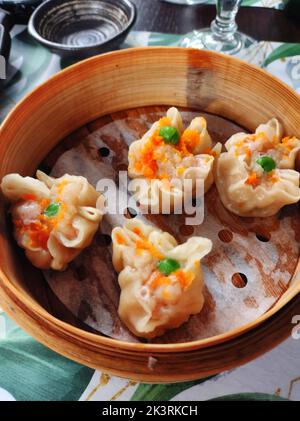 Ravioli al vapore nel cestino. Cibo cinese servito in un cestino di bambù Foto Stock