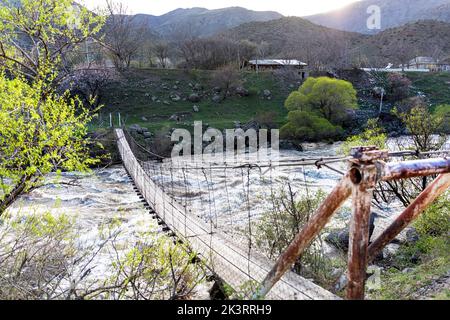 Vecchio ponte sospeso sul fiume Mtkvari in un bellissimo paesaggio di colori primaverili vicino al monastero grotta Vardzia in Georgia Foto Stock