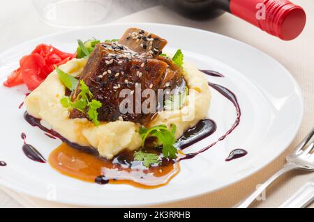 Stinco di agnello con purè di patate e asparagi. Foto Stock