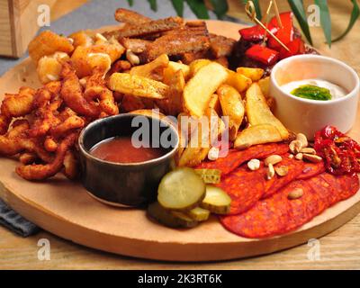 Gustosi snack assortiti e salse per birra su un asse di legno Foto Stock