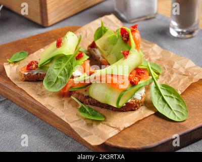 gustoso toast all'avocado con formaggio cremoso al cetriolo e pomodori secchi Foto Stock