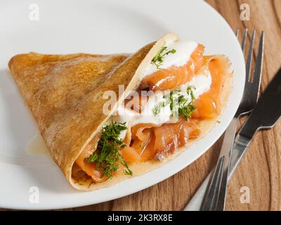 gustosa frittella con salmone e formaggio cremoso su un piatto bianco Foto Stock