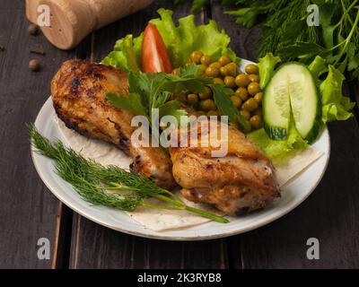 gustoso bastone di pollo alla griglia decorato con verdure su un piatto bianco Foto Stock