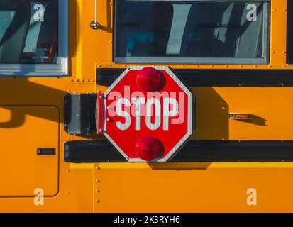 Close up di un ottagono rosso a forma di stop con luci di segnale su un bus di scuola Foto Stock