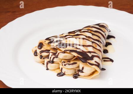 frittella con banana e cioccolato su un piatto bianco Foto Stock