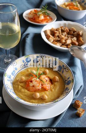 Deliziosa zuppa di ceci decorata con gamberetti. Sfondo grigio. Direttamente sopra. Cibo sano, dieta, ricetta o concetto di menu. Foto Stock