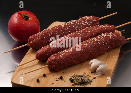 Gustoso kebab di lula crudo con spezie su un asse di legno Foto Stock