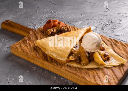 Crepes farcite con frutta e noci. Servito con palla di gelato. Frittelle sottili, dessert dolce Foto Stock