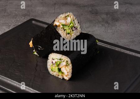 sushirrito gustoso con pollo e verdure su una pietra scura Foto Stock