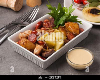 gustoso antipasto caldo patate salsicce pollo e maiale con cipolla e salsa Foto Stock