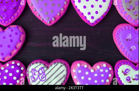 Splendide cornici di cuore rosa viola a forma di cuore con adorabili biscotti motivo su sfondo nero Foto Stock