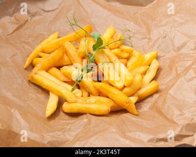 gustose patatine fritte decorate con piselli micro-verdi su carta artigianale Foto Stock