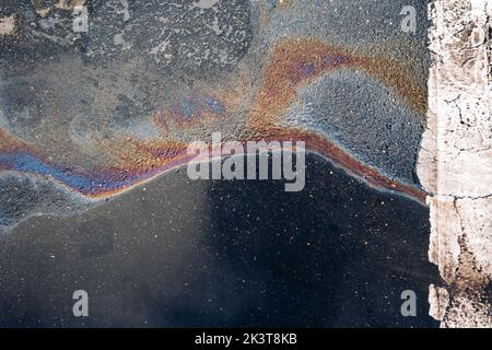 Fuoriuscita di benzina sull'asfalto in un parcheggio come texture o sfondo. Foto Stock