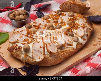 gustosa pizza con tacchino e funghi su un asse di legno Foto Stock