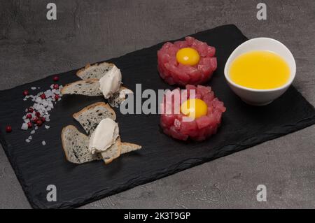 gustose tartare di tonno con tuorlo, crostini e formaggio cremoso Foto Stock