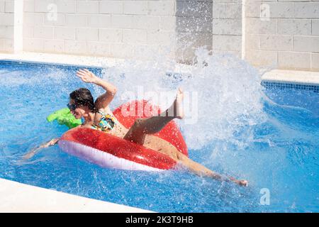 Dall'alto donna che prende il sole sull'anello gonfiabile e che spruzza in piscina Foto Stock