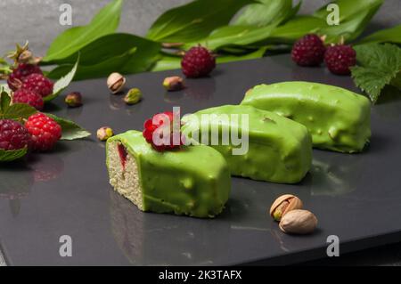 mini cupcake con ripieno di lamponi decorato con glassa al pistacchio Foto Stock