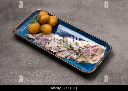 gustose aringhe salate con patate sbucciate, guarnite con capperi e cipolla rossa Foto Stock