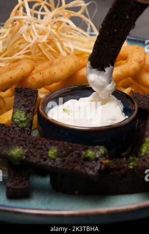 gustosi spuntini alla birra: anelli di cipolla, crostini all'aglio, formaggio con salsa di panna acida. Primo piano Foto Stock