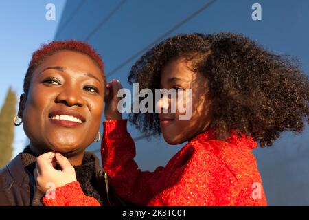 Allegro africano americano bambino guardando madre felice sulla strada in giorno di sole Foto Stock