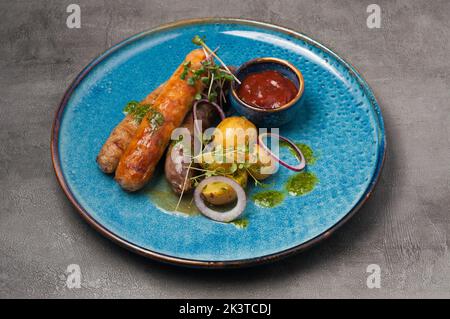 gustose salsicce alla griglia assortite con patate novelle, salsa di pomodoro e burro verde Foto Stock