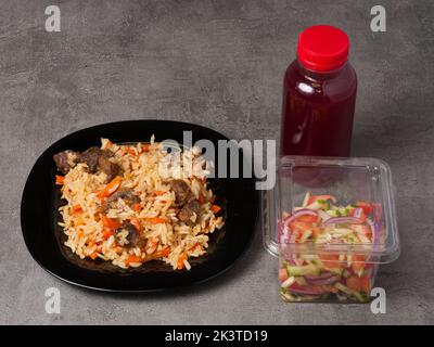 Gustoso pilaf uzbeko, insalata di verdure e bevande. Pranzo a menu fisso Foto Stock