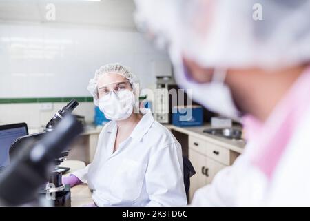 vista in prima persona di uomini e donne scienziati che si guardano l'un l'altro in laboratorio Foto Stock