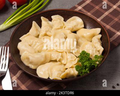 gnocchi russi con pollo su un piatto di argilla decorato con erbe Foto Stock