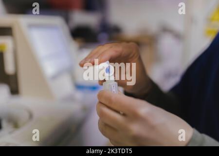 Vista laterale delle mani del farmacista che mescolano medicinali in bottiglia su sfondo sfocato Foto Stock