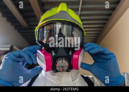 Pompiere che mette su maschera per disinfettare un edificio Foto Stock