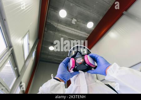 Pompiere che mette su maschera per disinfettare un edificio Foto Stock