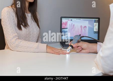 Concetto di diagnosi della sclerosi sistemica, le mani di un medico e di un paziente sono visibili con i macchinari di diagnosi. Foto Stock