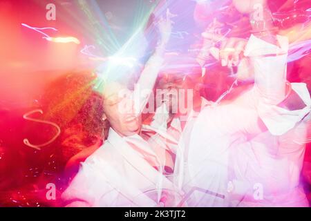 Una coppia afro-americana ubriaca urlando e ballando sotto la luminosa luce al neon mentre si diverte durante la festa Foto Stock
