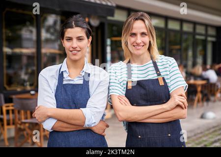 Foto intermedia di due imprenditori di ristoranti femminili che si pongono di fronte al loro negozio Foto Stock