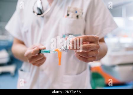 Mani a fuoco morbido siringa di riempimento del medico non riconoscibile con soluzione dalla fiala per iniezione in clinica Foto Stock