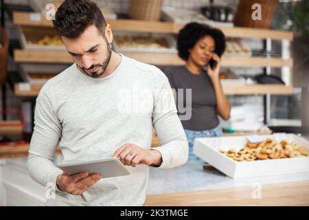 Proprietario di un panificio che imposta il negozio online su un tablet digitale Foto Stock