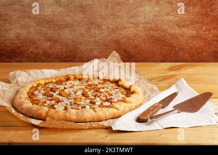 Torta fatta in casa con prugne e petali di mandorle su carta pergamena. CopySpace. Foto Stock